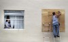 A King Point resident looks through her broken window as a man boards up a broken window from an apparent overnight tornado spawned from Hurricane Ian at Kings Point 55+ community in Delray Beach, Fla., on Wednesday, Sept. 28, 2022.   (Carline Jean /South Florida Sun-Sentinel via AP)