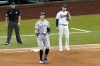 New York Yankees' Aaron Judge, center, rounds first after hitting a single as umpire Randy Rosenberg, left, and Texas Rangers first baseman Nathaniel Lowe, right, look on in the eighth inning of the first baseball game of a doubleheader in Arlington, Texas, Tuesday, Oct. 4, 2022. (AP Photo/Tony Gutierrez)