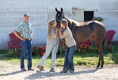 George Williams / Winnipeg Free Press
                                Trainer Mike Nault smiles as grooms Charlotte (left) and Olive Johnston smooch Osiris Stakes winner Lady Cop.