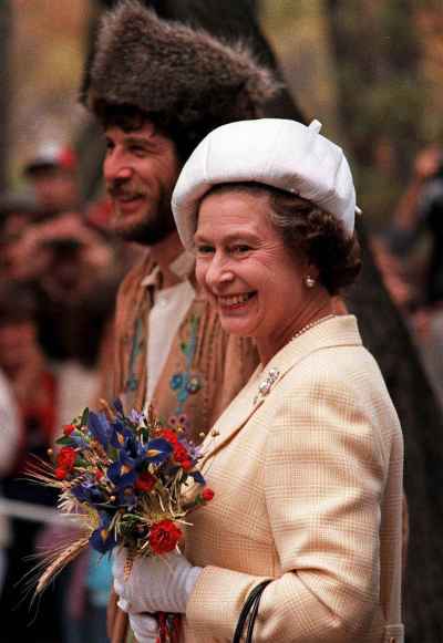 After watching canoeists land on the banks of the Red River in Winnipeg, MB, Oct. 6, 1984, Queen Elizabeth II goes on a walkabout with one of the canoeists dressed as explorer Pierre LaVerendrye into LaVerendrye Park. ( CP PHOTO/Nick Didlick)