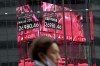 A person wearing a protective mask walks in front of an electronic stock board showing Japan's Nikkei 225 index at a securities firm Friday, Oct. 14, 2022, in Tokyo. Asian shares were mostly lower on Thursday after Wall Street benchmarks fell, reversing course after two days of gains. (AP Photo/Eugene Hoshiko, File)