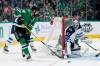 Jamie Benn makes a pass to the front of the net as Winnipeg Jets goaltender Connor Hellebuyck holds the post in the first period on Monday. (Tony Gutierrez / The Associated Press)