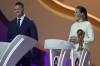 FILE - Former American soccer international Carli Lloyd, right, and Jermaine Jenas, English television presenter, pundit and retired professional soccer player assist with the 2022 soccer World Cup draw at the Doha Exhibition and Convention Center in Doha, Qatar, Friday, April 1, 2022. (AP Photo/Darko Bandic, File)