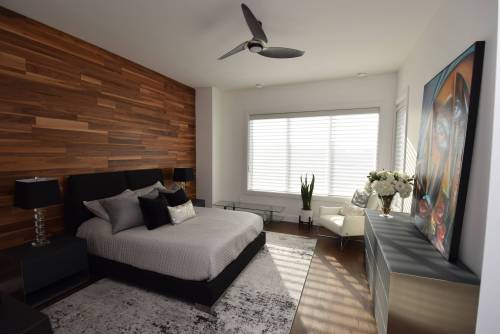 Cappuccino-stained oak hardwoods and a walnut feature wall warm up the primary bedroom.