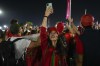 Morocco soccer team fan uses her mobile phone as supporters cheer while they their walk towards Al Bayt Stadium prior of the World Cup semifinals soccer match between France and Morocco in Doha, Qatar, Wednesday, Dec. 14, 2022. (AP Photo/Frank Augstein)