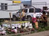 An RCMP officer patrols the entrance to the Port Coquitlam pig farm behind a fence and a memorial to some of the fifty missing women, as the search continues for their remains on the farm Wednesday June 26, 2002. THE CANADIAN PRESS/Chuck Stoody