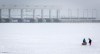 A couple heads out to clear an area of snow on the ice of Ghost Lake Reservoir beside at Transalta hydro-electric dam near Cochrane, Alta., Sunday, Dec. 27, 2020. Alberta's frigid temperatures this week have prompted the province's electrical system operator to declare a grid alert. THE CANADIAN PRESS/Jeff McIntosh