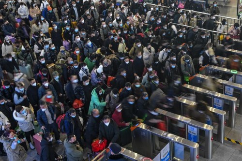 In this photo released by Xinhua News Agency, People wearing face masks with their luggage line up to enter the ticket counters to catch their trains at the railway station in Suzhou in east China's Jiangsu Province, Saturday, Jan. 7, 2023. China is now facing a surge in COVID-19 outbreak cases and hospitalizations in major cities and is bracing for a further spread into less developed areas with the start of the Lunar New Year travel rush, set to get underway in coming days. (Li Bo/Xinhua via AP)