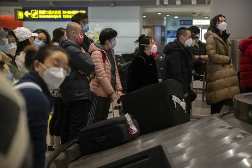 Travelers wearing face masks wait for their luggage in the international arrivals area at Beijing Capital International Airport in Beijing, Monday, Jan. 9, 2023. The first international travelers are arriving in China without the mandatory quarantine that had been imposed at the start of the pandemic three years ago after restrictions were lifted beginning on Sunday. (AP Photo/Mark Schiefelbein)