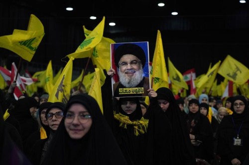 FILE - A Hezbollah supporter holds up a picture of the leader of Lebanon's Iran-backed Hezbollah leader Sayyed Hassan Nasrallah, during a ceremony to mark the third anniversary of the assassination of Iran's Quds force General Qassem Soleimani, who was killed in a U.S. drone strike in Baghdad, in the southern Beirut suburb of Dahiyeh, Lebanon, on Jan. 3, 2023. Lebanon's militant Hezbollah group on Tuesday, Jan. 10, 2023 condemned the cartoons published recently by the French satirical magazine Charlie Hebdo that mocked Iran's ruling clerics and urged France to punish the publication. (AP Photo/Bilal Hussein, File)