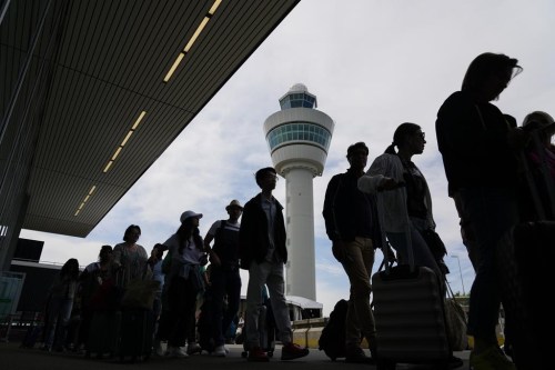 FILE - Travelers wait in line outside the terminal building to check in and board flights at Amsterdam's Schiphol Airport, Netherlands, on June 21, 2022. Travelers whose package tours were ruined by the imposition of restrictions to combat the COVID-19 pandemic may be entitled to at least a partial refund, the European Union's highest court said Thursday, Jan. 12, 2023. (AP Photo/Peter Dejong, File)