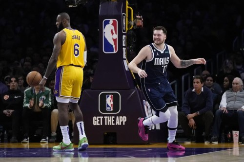 Dallas Mavericks' Luka Doncic (77) smiles after making a basket against Los Angeles Lakers' LeBron James (6) during the first half of an NBA basketball game Thursday, Jan. 12, 2023, in Los Angeles. (AP Photo/Jae C. Hong)