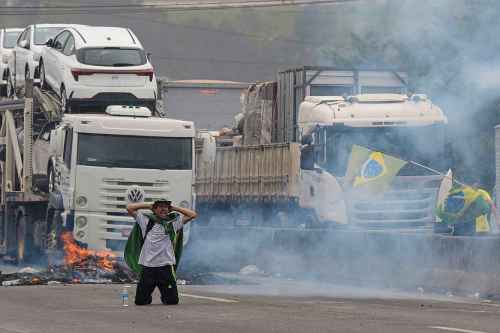 A protester kneels with his hands behind his head as riot police launch tear gas at truckers blocking a highway in protest against President Jair Bolsonaro's loss in the country's presidential runoff election, in Embu das Artes, outskirts of Sao Paulo, Brazil, Tuesday, Nov. 1, 2022.  Since the former President Luiz Inacio Lula da Silva's victory Sunday night, many truck drivers have jammed traffic in areas across the country and said they wonâ€™t acknowledge Bolsonaroâ€™s defeat. Bolsonaro hasnâ€™t spoken publicly since official results were released roughly 36 hours ago, nor phoned da Silva to concede. (AP Photo/Andre Penner)