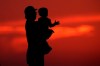 Pandemic benefits rolled out to cushion the blow of COVID-19 lockdowns had the unintended consequence of dramatically reducing poverty levels, and now, a group is calling on the federal government to build on that success. A silhouette against the sky of a man holding a child in Kansas City, Mo., Friday, June 26, 2020. THE CANADIAN PRESS/AP-Charlie Riedel