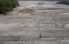 FILE - A man walks across an almost dried up bed of river Yamuna amid hot weather in New Delhi, India, May 2, 2022. Indian authorities need more resources and better preparation to deal with searing heat particularly for the most vulnerable communities around the country, a New Delhi-based think tank said. (AP Photo/Manish Swarup, File)
