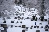 FILE - A man walks through the snow covered Mount Lebanon Cemetery in Mount Lebanon, Pa., on Monday, Jan. 23, 2023. U.S. deaths fell in 2022, as COVID-19 fatalities dropped by half from 2021 and the coronavirus dropped from being the nation's third leading cause of death to the fourth. The Centers for Disease Control and Prevention reported the 2022 numbers on Thursday, May 4, 2023, cautioning that they are preliminary and may change a little after further analysis. (AP Photo/Gene J. Puskar, File)