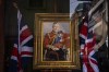 An employee arranges a shop window decorated with a painting of King Charles III in London, Thursday, May 4, 2023. The Coronation of King Charles III will take place at Westminster Abbey on May 6. (AP Photo/Emilio Morenatti)