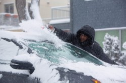 Junior Munyaka clears off his car. (Mike Deal / Winnipeg Free Press)