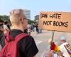Ash Laing holds up a protest sign on the Manitoba Legislative Building grounds in protest of book banning requests on Tuesday. (Maggie MacIntosh / Winnipeg Free Press)