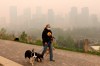 Wearing a protective mask, dog walker Leslie Kramer ventures out as heavy smoke from northern Alberta forest fires comes south to blanket the downtown area in Calgary, Tuesday, May 16, 2023. As air quality due to wildfire smoke remains poor in parts of Western Canada, health experts are advising people to stay inside as much as possible. THE CANADIAN PRESS/Larry MacDougal