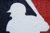 Rain drops cover a Major League Baseball logo as weather delays a baseball game between the Philadelphia Phillies and the Atlanta Braves, Wednesday, June 21, 2023, in Philadelphia. (AP Photo/Matt Slocum)
