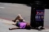 FILE - A homeless person lies on the sidewalk while holding a water bottle, Sunday, July 2, 2023, in downtown Los Angeles. Excessive heat warnings remain in place in many areas across the U.S. and are expected to last at least through Monday. (AP Photo/Damian Dovarganes, File)