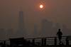 Seth Wenig / The Associated Press Files
                                A man runs in front of the sun rising over the lower Manhattan skyline in Jersey City, N.J., last month. Thick, smoky air from Canadian wildfires has made for days of misery as far away as New York City and across the U.S. Northeast.
