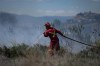 Wildfire crews across British Columbia are keeping a close eye on the backcountry after recent lightning storms have raised the potential for smouldering fires to erupt as the next hot spell arrives this weekend. A firefighter directs water on a grass fire in Kamloops, B.C., Monday, June 5, 2023. THE CANADIAN PRESS/Darryl Dyck