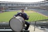 FILE - Cleveland Indians fan John Adams poses in his usual centerfield bleacher seat with his ever present bass drum before a baseball game April 27, 2011, between the Indians and the Kansas City Royals in Cleveland. The Guardians are naming their left-field bleachers at Progressive Field in honor of Adams, the longtime drummer who died early this year. (AP Photo/Amy Sancetta, File)