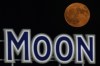 FILE - A supermoon rises beyond a beer sign at Kauffmann Stadium during a baseball game between the Kansas City Royals and the New York Mets, Aug. 1, 2023, in Kansas City, Mo. Stargazers are in for a double treat on Wednesday night, Aug. 30: a rare blue supermoon with Saturn peeking from behind. The cosmic curtain rises Wednesday night with the second full moon of August, the reason it’s considered blue. It’s dubbed a supermoon because it’s closer to Earth than usual, appearing especially big and bright. (AP Photo/Charlie Riedel, File)
