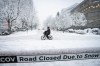 A person cycles past a road closed sign during a snowstorm in Vancouver Wednesday, Jan. 17, 2024.&nbsp;A winter storm closed schools and disrupted flights in B.C. on Wednesday, with snow expected to continue in some parts of the province.THE CANADIAN PRESS/Ethan Cairns