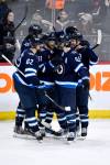 Winnipeg Jets left wing Kyle Connor (81) celebrates his game-winning goal against the Arizona Coyotes with Nino Niederreiter (62) and Mark Scheifele (55) during overtime NHL action in Winnipeg on Sunday February 25, 2024. THE CANADIAN PRESS/Fred Greenslade