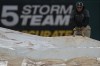A grounds crew member helps remove the tarp from the field after a rain delay of a baseball game between the Colorado Rockies and the Chicago White Sox, Friday, June 28, 2024, in Chicago. (AP Photo/Erin Hooley)
