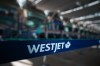 Travellers passing through airports are wondering if they'll be able to catch their WestJet flight this Canada Day long weekend. A WestJet logo is seen in the domestic check-in area at Vancouver International Airport, in Richmond, B.C., on Friday, May 19, 2023. THE CANADIAN PRESS/Darryl Dyck