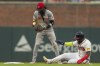 Cincinnati Reds shortstop Elly De La Cruz checks the ball as Atlanta Braves' Marcell Ozuna, right, slides into second base in the fourth inning of a baseball game, Monday, July 22, 2024, in Atlanta. (AP Photo/Jason Allen)