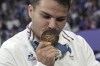 Antoine Dupont of France kisses his gold medal as he celebrates after France won the men's Rugby Sevens gold medal at the 2024 Summer Olympics, in the Stade de France, in Saint-Denis, France, Saturday, July 27, 2024. France defeated Fiji in the gold medal match 28-7. (AP Photo/Tsvangirayi Mukwazhi)