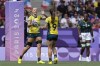 Australia's Maddison Levi hands the ball to teammate Tia Hinds, as she celebrates after scoring try during the women's Pool B Rugby Sevens match between Australia and South Africa at the 2024 Summer Olympics, in the Stade de France, in Saint-Denis, France, Sunday, July 28, 2024. (AP Photo/Tsvangirayi Mukwazhi)