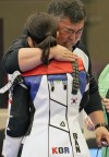 South Korea's Ban Hyojin is hugged by her coach after winning the 10m air rifle women's final as the third-place holder Switzerland's Audrey Gogniat looks on at the 2024 Summer Olympics, Monday, July 29, 2024, in Chateauroux, France. (AP Photo/Manish Swarup)