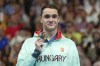 Hungary's Kristof Milak poses with the gold medal on the podium for the men's 100-meter butterfly at the Summer Olympics in Nanterre, France, Saturday, Aug. 3, 2024. (AP Photo/Natacha Pisarenko)