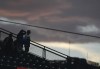 Fans are silhouetted against the clouds as a rainstorm sweeps over Coors F/ield in the fifth inning of a baseball game between the New York Mets and Colorado Rockies, Tuesday, Aug. 6, 2024, in Denver. (AP Photo/David Zalubowski)