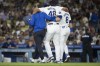 Los Angeles Dodgers relief pitcher Brusdar Graterol (48) is helped getting out of a baseball game against the Philadelphia Phillies due to an apparent injury in Los Angeles, Tuesday, Aug. 6, 2024. (AP Photo/Kyusung Gong)