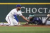 Texas Rangers second base Marcus Semien, left, tags Seattle Mariners' J.P. Crawford out at second base as Crawford tries to the stretch a single into a double during the sixth inning of a baseball game, Saturday, Sept. 21, 2024, in Arlington, Texas. (AP Photo/LM Otero)
