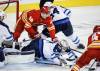 JEFF MCINTOSH / THE CANADIAN PRESS
                                Goalie Connor Hellebuyck dives for the puck as Calgary Flames&rsquo; Sam Honzek (left) is is checked into him by Dylan Samberg during the third period in Calgary on Friday.