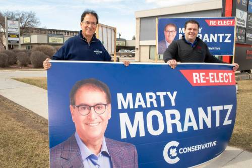 BROOK JONES / FREE PRESS
                                Incumbent Conservative candidate Marty Morantz (left) holds a large re-elect campaign sign with his campaign manager Michael Kowalson while the duo are pictured alongside Portage Avenue in Winnipeg, Man., Thursday, April 17, 2025. Morantz, who is a two-term Conservative incumbent, is running in the federal riding of Winnipeg West.