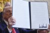 President Donald Trump holds a signed executive order during an event in the East Room of the White House, Tuesday, April 8, 2025, in Washington. (AP Photo/Evan Vucci)
