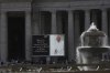 People walk in St. Peter's Square at the Vatican as a giant screen reports that a rosary prayer for the late Pope Francis has been scheduled for 19.30, Monday, April 21, 2025. THE CANADIAN PRESS/AP-Alessandra Tarantino