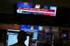 A screen displays financial news as traders work on the floor at the New York Stock Exchange in New York, Thursday, April 3, 2025. (AP Photo/Seth Wenig)