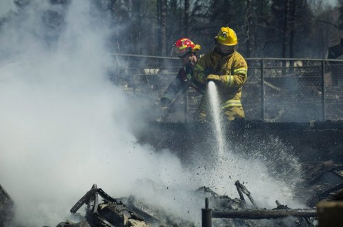 Firefighters work on the smouldering remains of houses in Slave Lake, Alta., on May 16, 2011. Slave Lake is one of six communities receiving funding to have an urban wildland firefighting team. THE CANADIAN PRESS/Ian Jackson