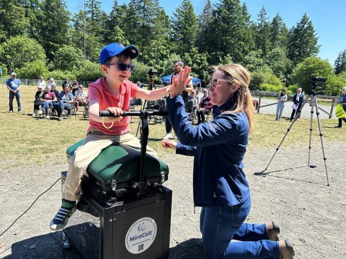 Six-year-old Casey, of Saanich B.C., becomes the first official user of the new MiraColt Horse-Riding Motion Simulator as Victoria Therapeutic Riding Association board chair Liz Gagel assists him at a demonstration hosted by the VTRA in Central Saanich, B.C. on Thursday, May 22, 2025. The simulator is the first of its kind by pairing a commercially available simulator with software developed at the University of Victoria in Victoria, B.C. to create a more authentic and motivating experience for riders. THE CANADIAN PRESS/Wolfgang Depner