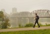 A person walks as the South Saskatchewan River is enveloped by forest fire smoke in Saskatoon, Sask., Sunday, Sept. 3, 2023. THE CANADIAN PRESS/Heywood Yu
